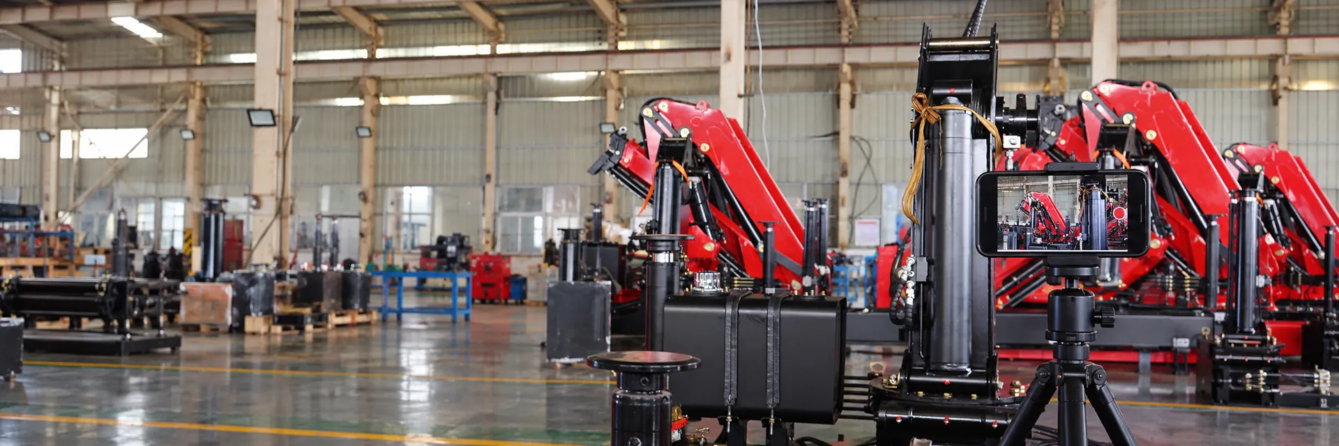 A phone on a tripod filming BOB-LIFT knuckle boom cranes in the workshop